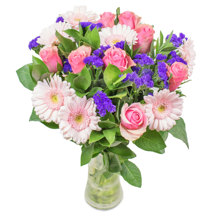 A refined and vibrant floral arrangement, this Hampton-inspired bouquet is showcased within a clear glass vase atop a snowy white backdrop. At its heart are approximately nine softly swirling pink roses, their petals just beginning to unfurl in classic spiral formations, evoking timeless romance. Paired exquisitely with seven pale pink gerbera daisies, their generous, radiant heads framed with lighter centers and pristine textures, the bouquet achieves a harmonious fusion of tones. Bright clusters of purple statice intermingle throughout, contributing striking contrast and a touch of exuberance reminiscent of the colourful flowerbeds in Hampton's parks. An abundance of rich, deep green foliage anchors the composition, conveying both abundance and freshness as though freshly gathered from the garden paths along the Thames. The transparent vase reveals neatly arranged stems immersed in clear water, completing this natural, fresh look-suggestive of a just-delivered bouquet or a thoughtful gift for occasions such as Mother's Day, anniversaries, or birthdays within the Hampton community. Crafted by experienced local florists, the presentation embodies celebration and affection, translating the beauty of Hampton's surroundings into floral poetry for home or office.